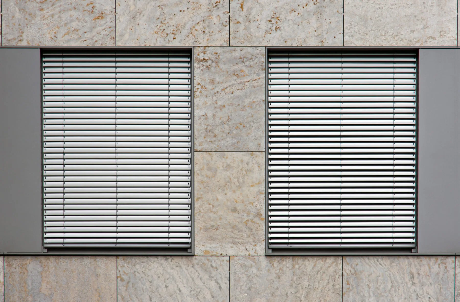 Zwei Fenster mit montierten Rollläden an einer hellen Fassade