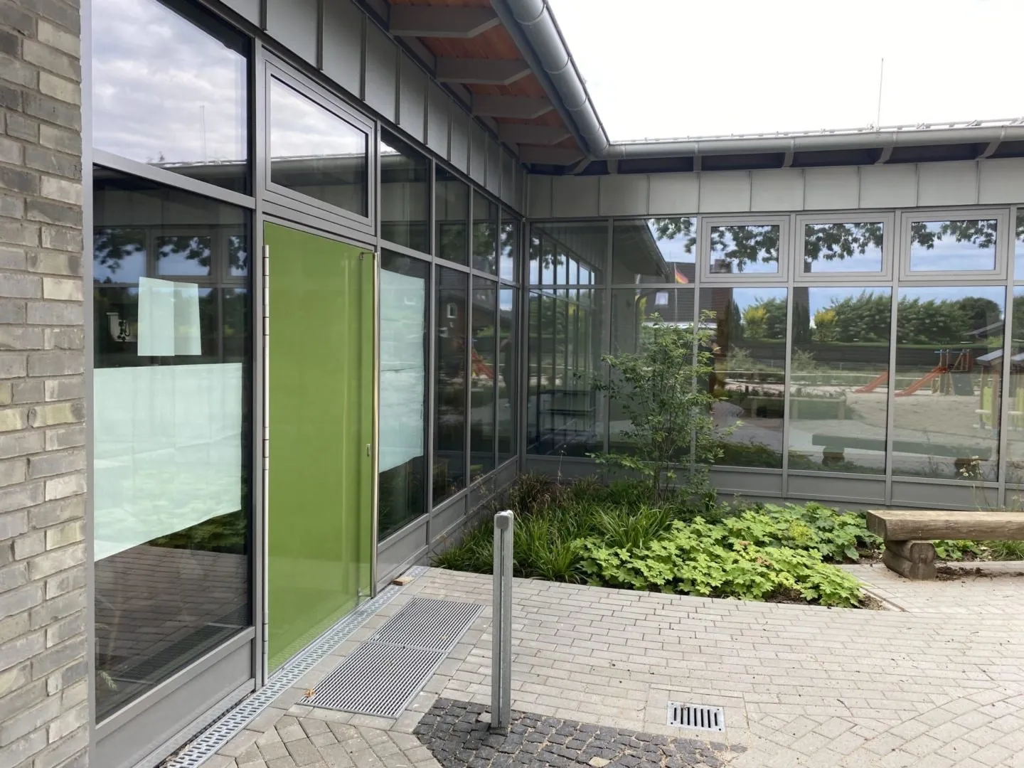 Grüne Aluminiumtür, eingebaut in eine Pfosten-Riegel-Fassade an einem Gebäudeeingang